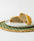 A Lehto's beef pasty cut in half on a white plate, showing the beef, potato, rutabaga and onion filling.