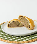 A Lehto's beef pasty cut in half, showing beef, potato, rutabaga and onion inside the golden crust.