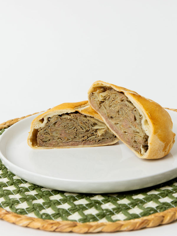 A Lehto's beef pasty cut in half, showing beef, potato, rutabaga and onion inside the golden crust.
