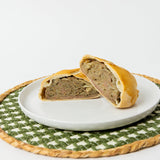 A Lehto's beef pasty cut in half, showing beef, potato, rutabaga and onion inside the golden crust.
