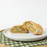 A Lehto's broccoli cheddar pasty cut in half, showing the broccoli and cheddar filling inside the golden crust.