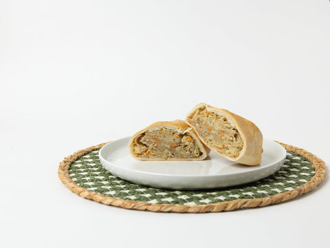 A Lehto's chicken pasty cut in half on a white plate, showing the chicken and vegetable filling.