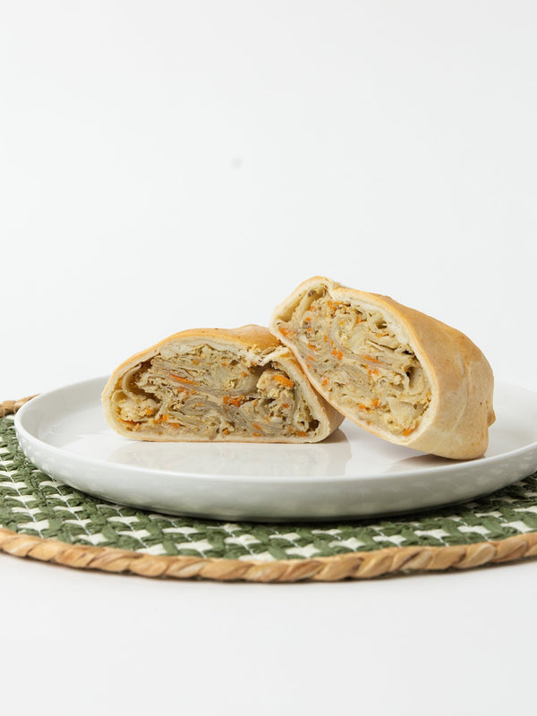 A Lehto's chicken pasty cut in half, showing the chicken and vegetable filling inside the golden crust.