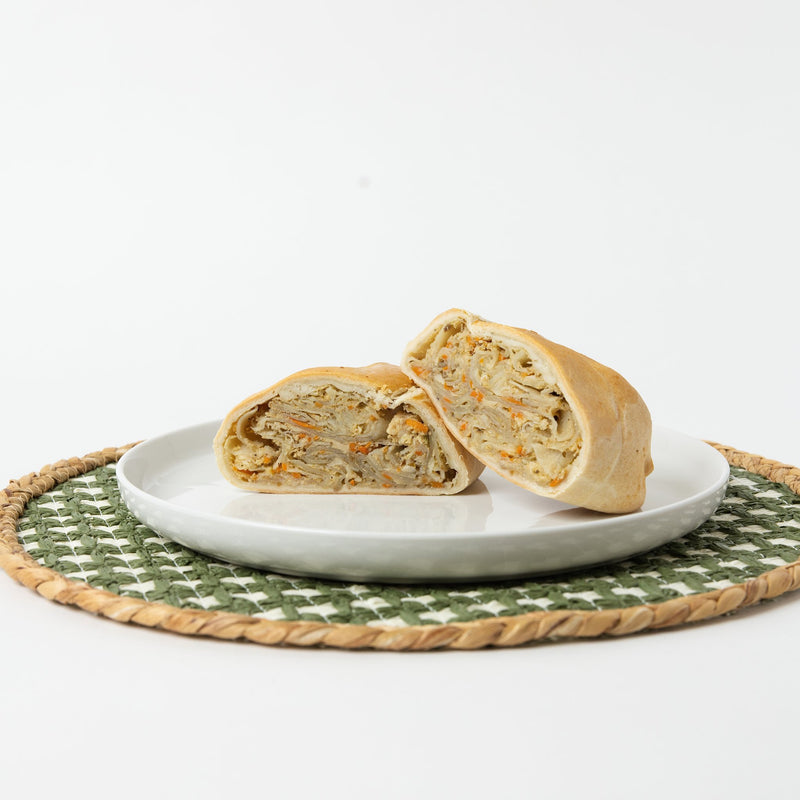 A Lehto's chicken pasty cut in half, showing the chicken and vegetable filling inside the golden crust.