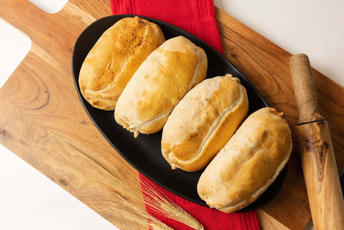 Four Lehto's pasties in a row on a black platter on a wooden board.